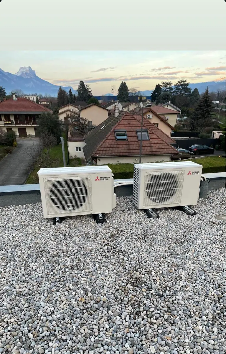 Deux unités extérieures de climatisation posées sur une toiture, avec vue sur les montagnes